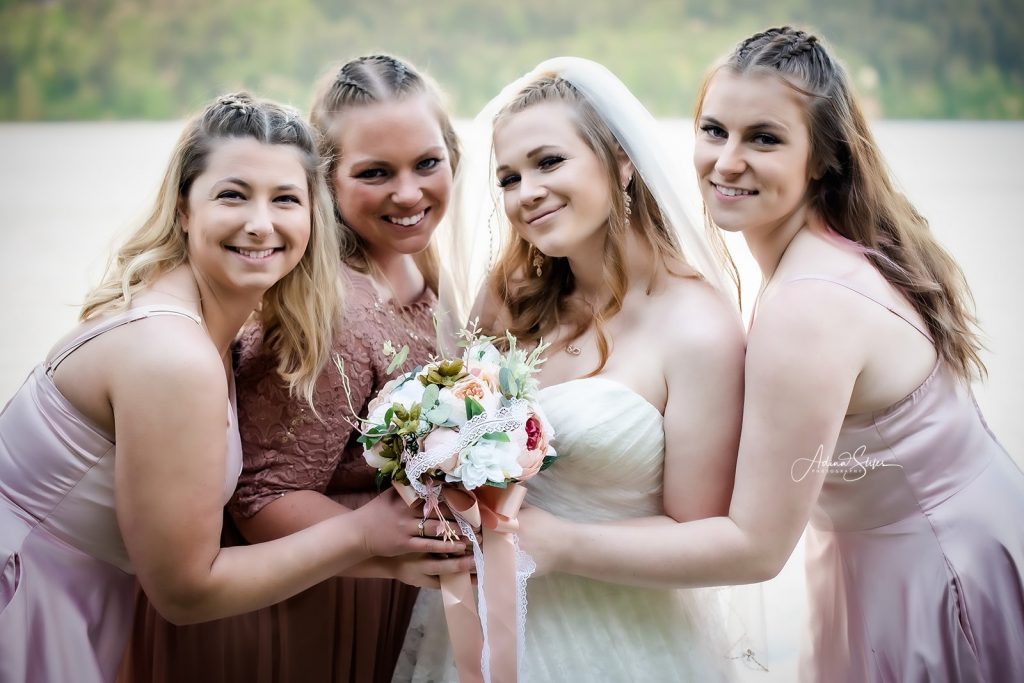 A bride hold a bouquet and smiles with her bridesmaids during an intimate wedding while Washington wedding photographer Adina Stiles captures the moment.